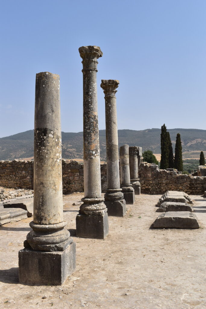 Viaggio in Marocco: colonne romane di Volubilis davanti alle colline del paesaggio marocchino